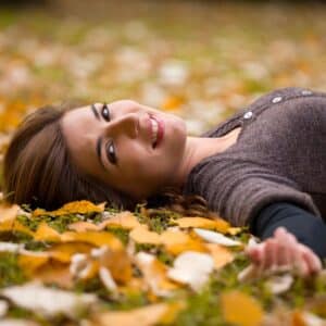 Woman laying in leaves looking relaxed