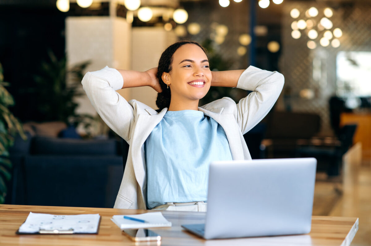 Confident woman at desk smiling after using mental health resources for freedom from stress