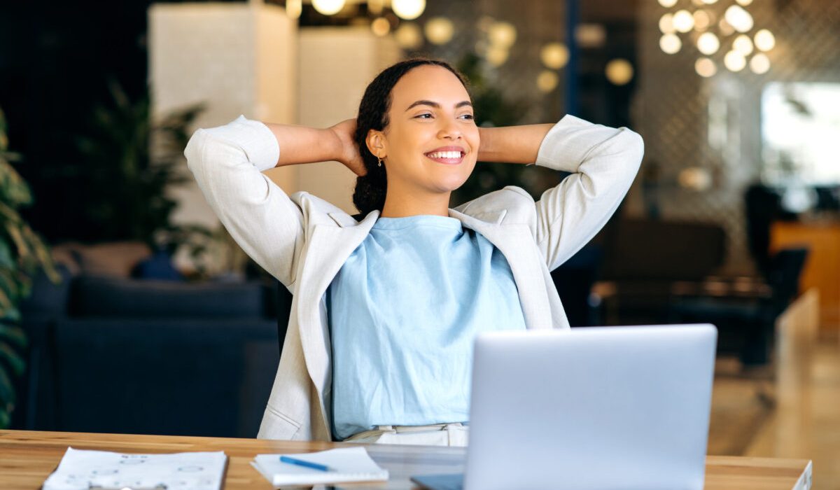 Confident woman at desk smiling after using mental health resources for freedom from stress